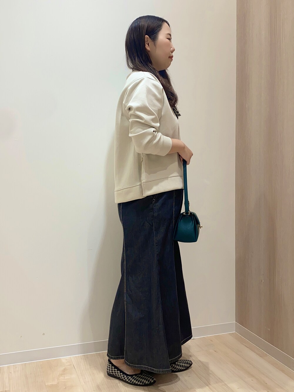 ベージュ系のTシャツ/カットソー、ブラック系のデニムスカート、グリーン系のショルダーバッグを着用したレディースの秋コーディネートの3枚目の写真