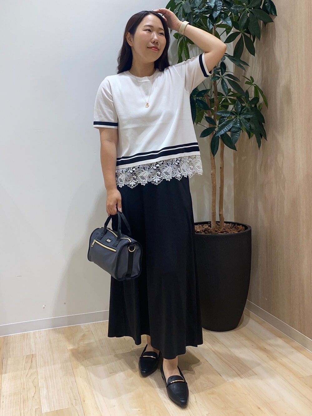 ホワイト系のニット/セーター、ブラック系のスカート、グレー系のボストンバッグを着用したレディースの夏コーディネートの2枚目の写真