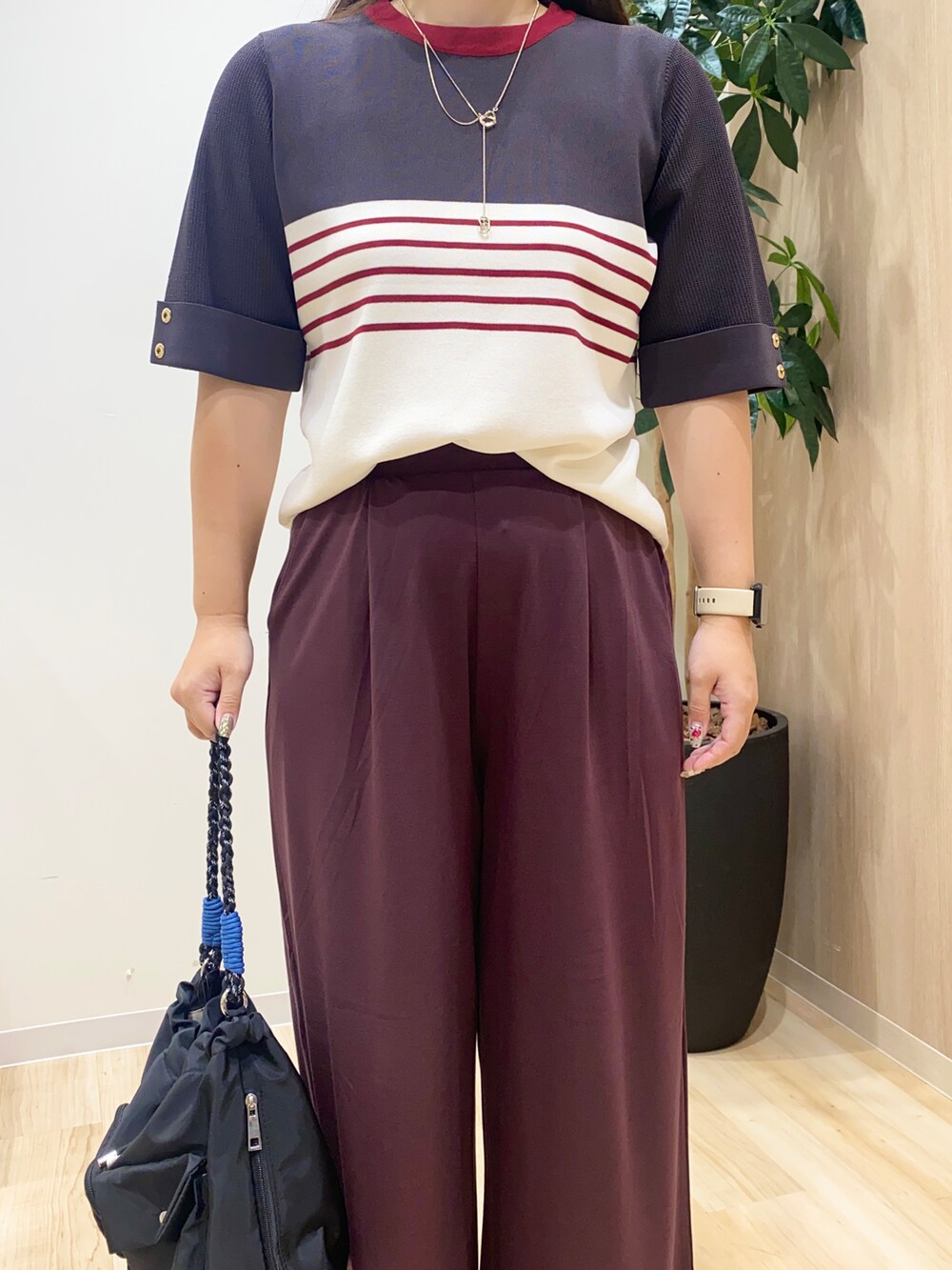 グレー系のニット/セーター、ブラウン系のその他パンツ、ブラック系のショルダーバッグを着用したレディースの夏コーディネートの5枚目の写真