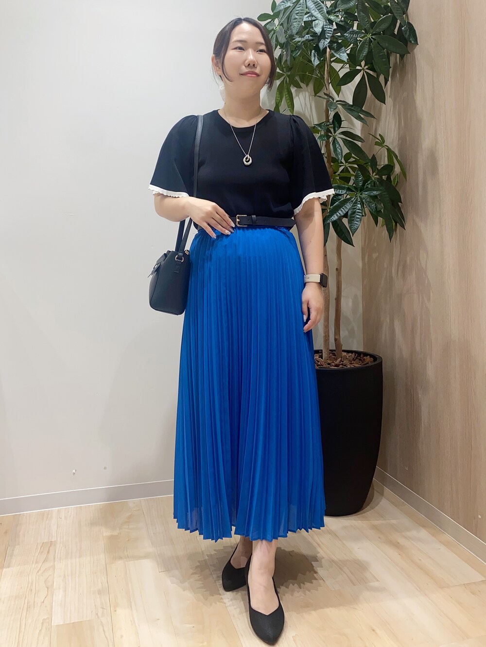 ブラック系のニット/セーター、ブルー系のスカート、ブラック系のショルダーバッグを着用したレディースの夏コーディネートの2枚目の写真