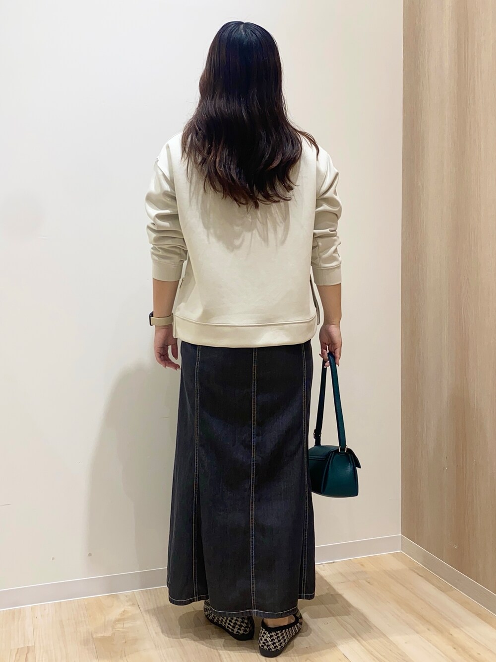 ベージュ系のTシャツ/カットソー、ブラック系のデニムスカート、グリーン系のショルダーバッグを着用したレディースの秋コーディネートの4枚目の写真