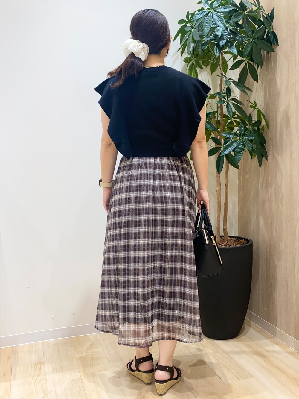 ブラック系のワンピース、ブラック系のトートバッグ、ゴールド系のネックレスを着用したレディースの夏コーディネートの4枚目の写真