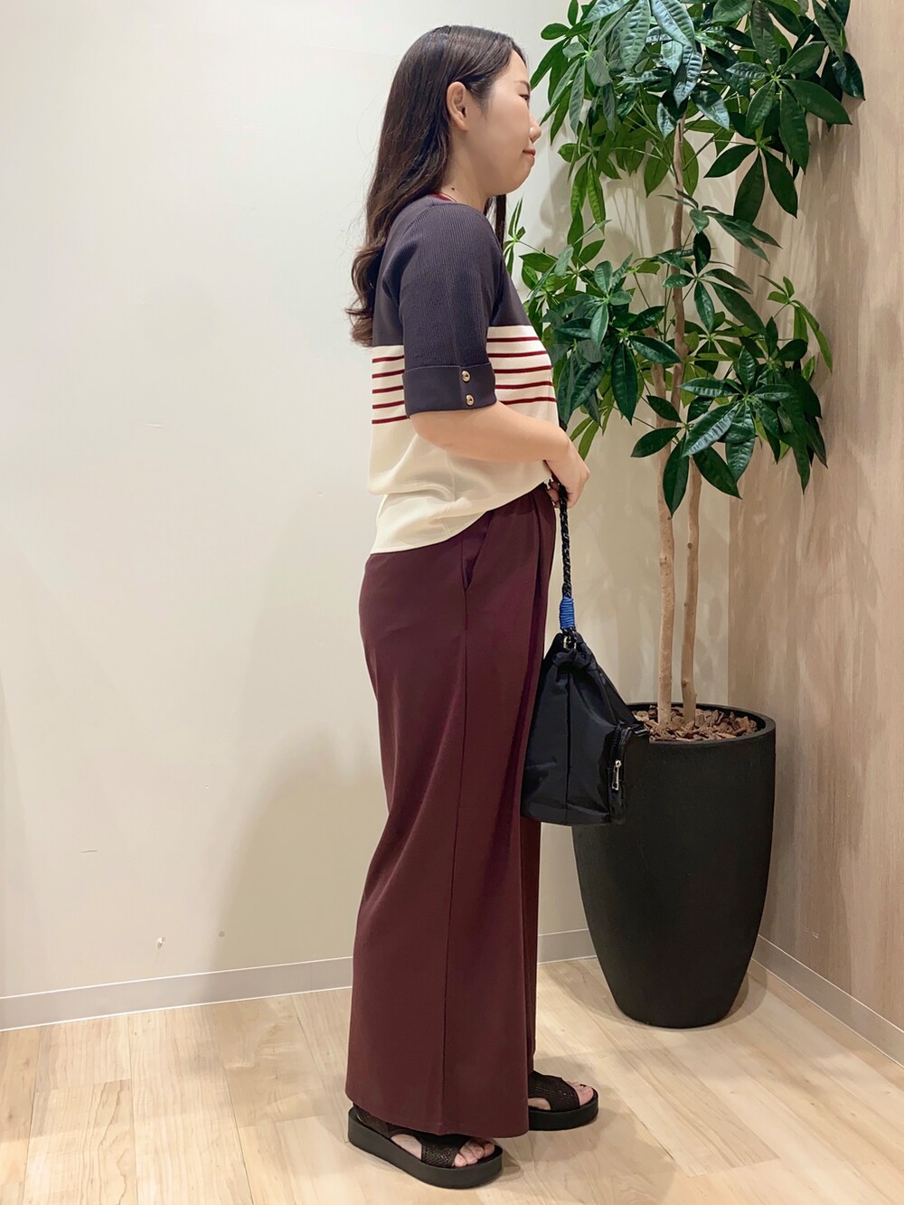 グレー系のニット/セーター、ブラウン系のその他パンツ、ブラック系のショルダーバッグを着用したレディースの夏コーディネートの3枚目の写真
