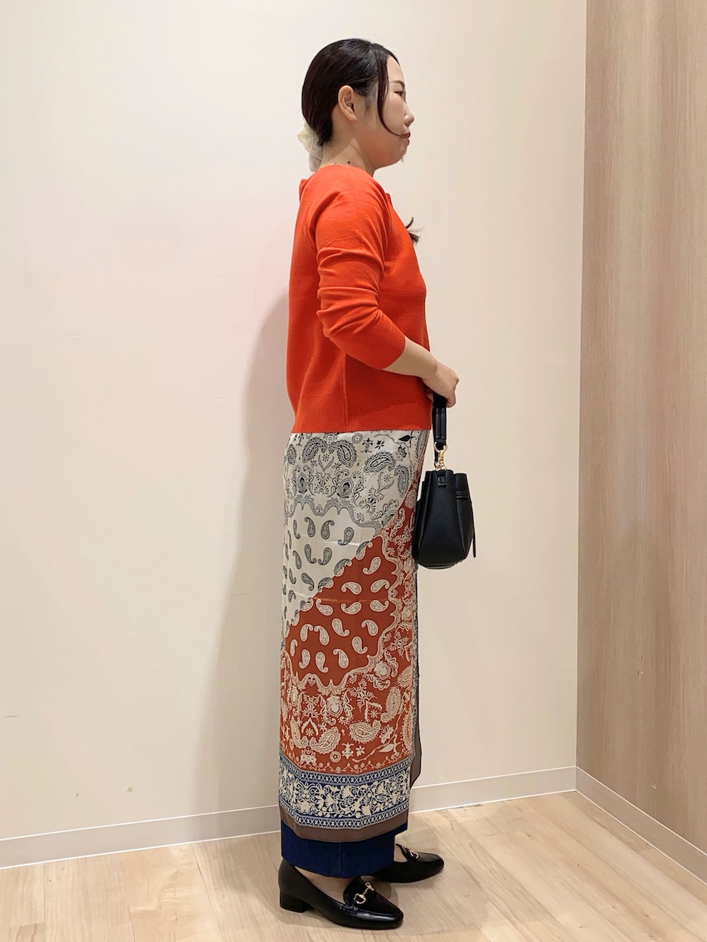 レッド系のニット/セーター、ブルー系のデニムパンツ、ブラック系のショルダーバッグを着用したレディースの秋コーディネートの4枚目の写真