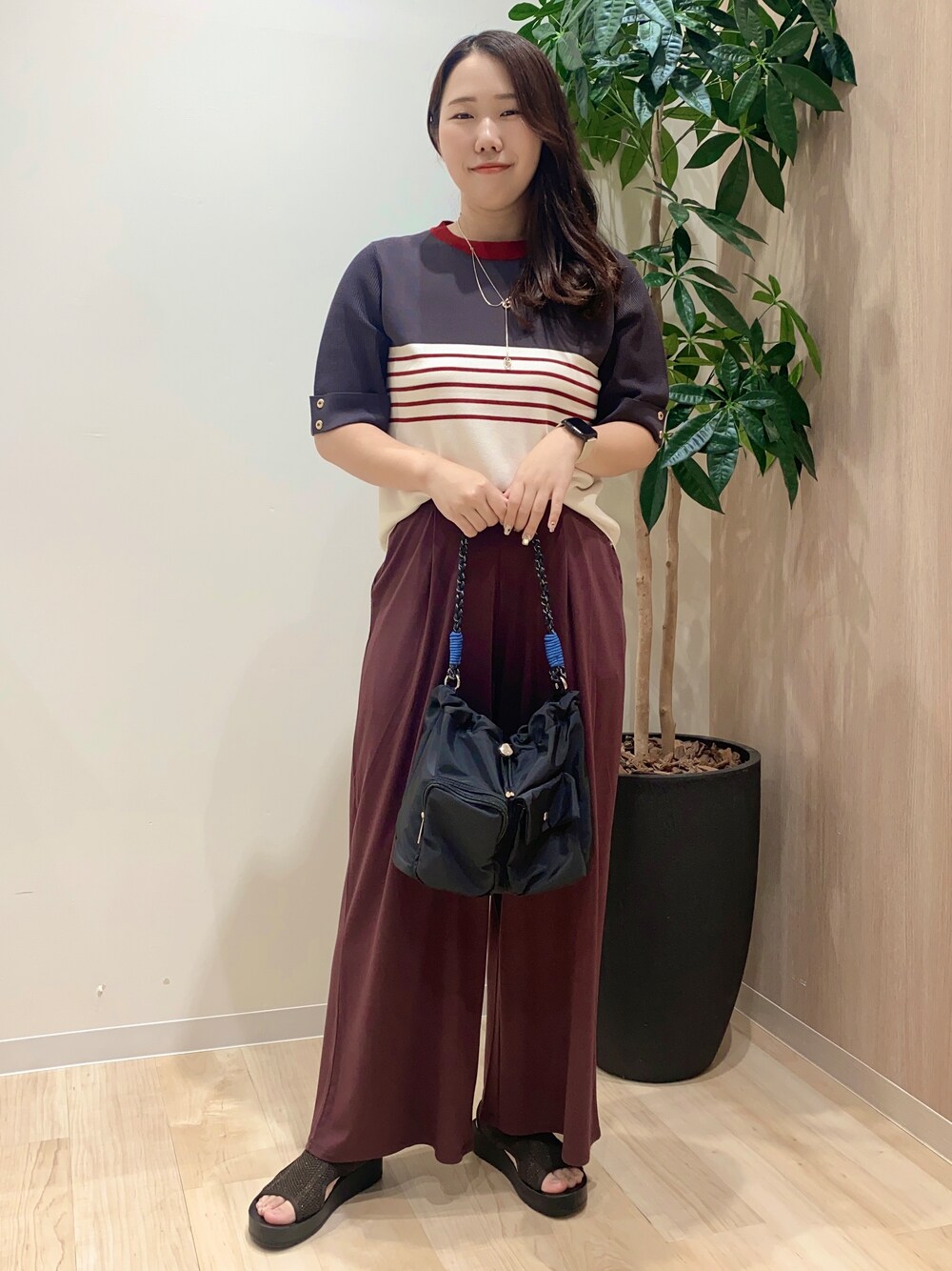 グレー系のニット/セーター、ブラウン系のその他パンツ、ブラック系のショルダーバッグを着用したレディースの夏コーディネートの2枚目の写真