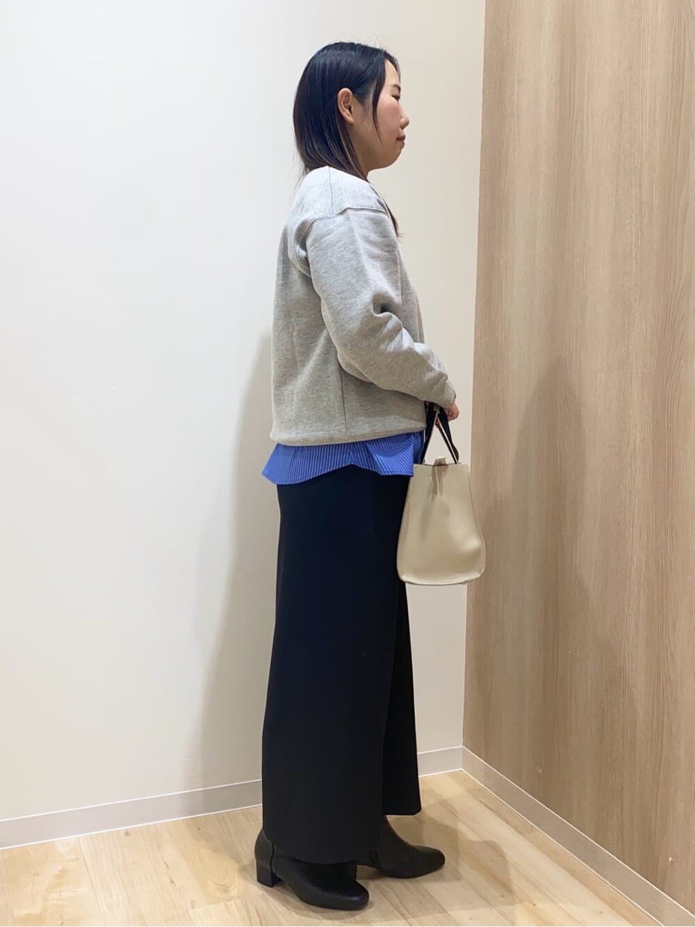 グレー系のスウェット、ブルー系のタンクトップ、ブラック系のスカートを着用したレディースの冬コーディネートの2枚目の写真