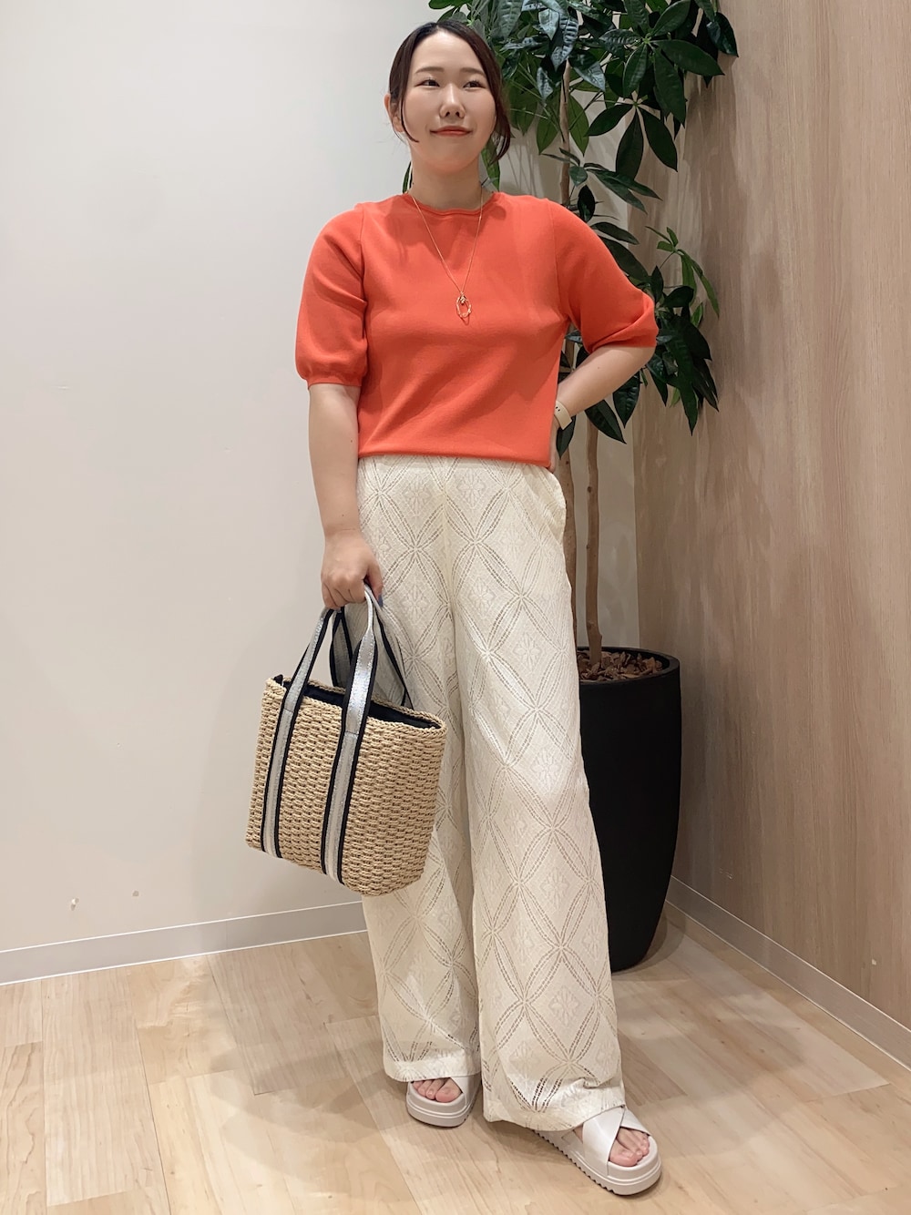 レッド系のニット/セーター、ホワイト系のその他パンツ、ベージュ系のトートバッグを着用したレディースの夏コーディネートの2枚目の写真