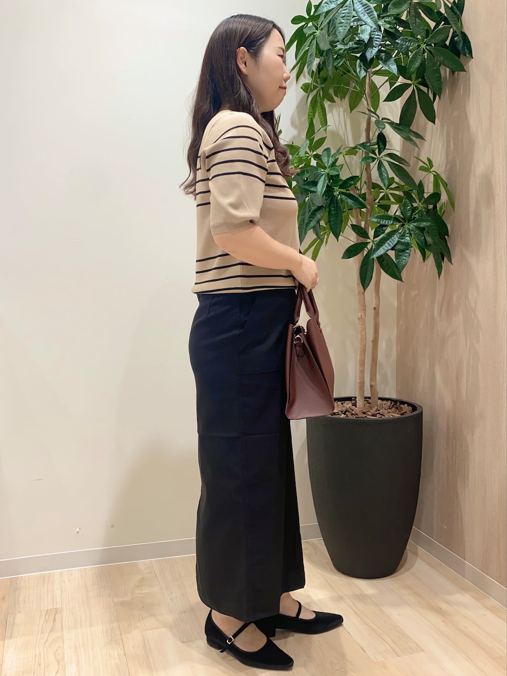 ベージュ系のニット/セーター、ブラック系のスカート、レッド系のトートバッグを着用したレディースの夏コーディネートの3枚目の写真