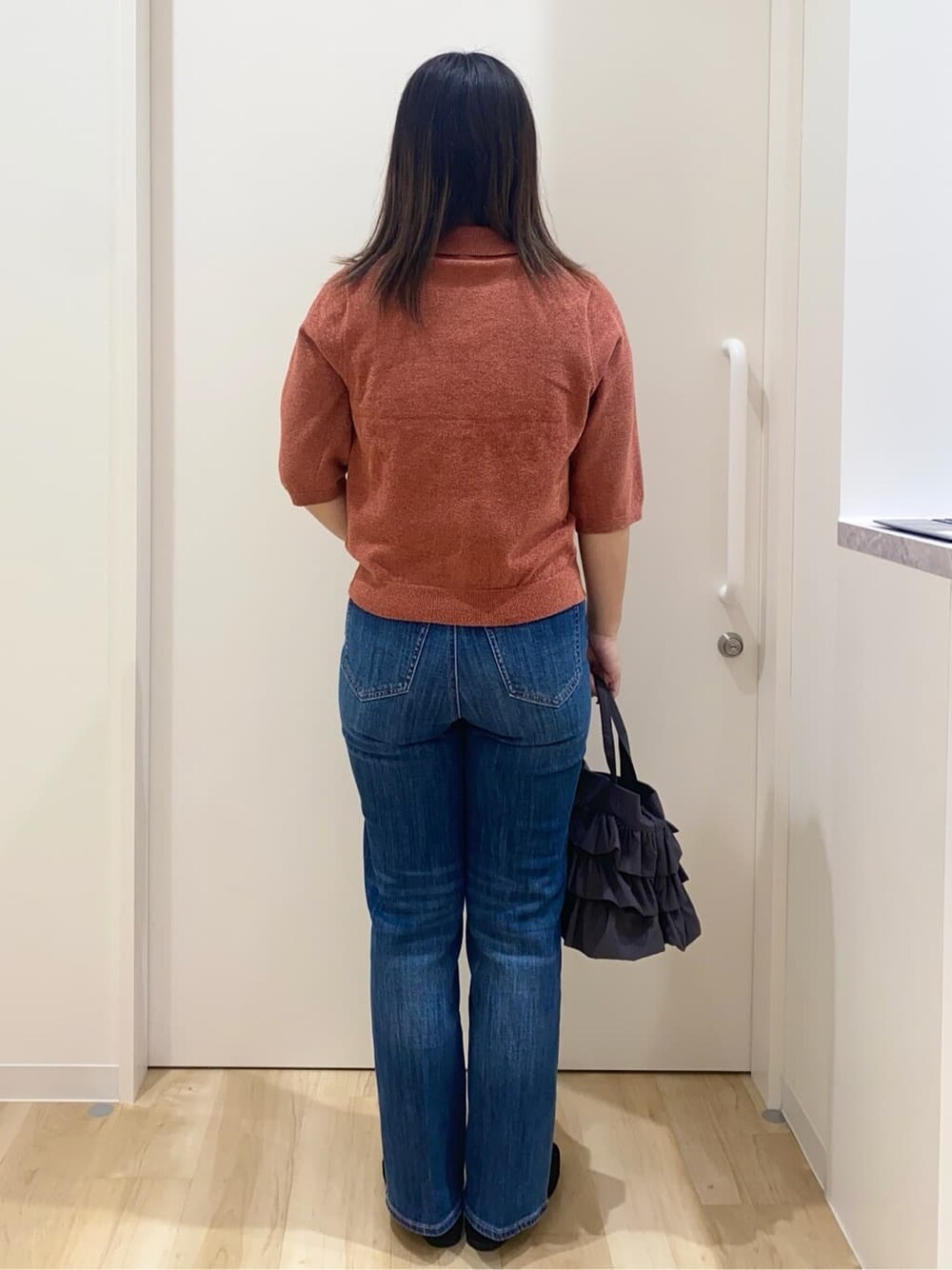 レッド系のニット/セーター、ブルー系のデニムパンツ、グレー系のトートバッグを着用したレディースの秋コーディネートの3枚目の写真