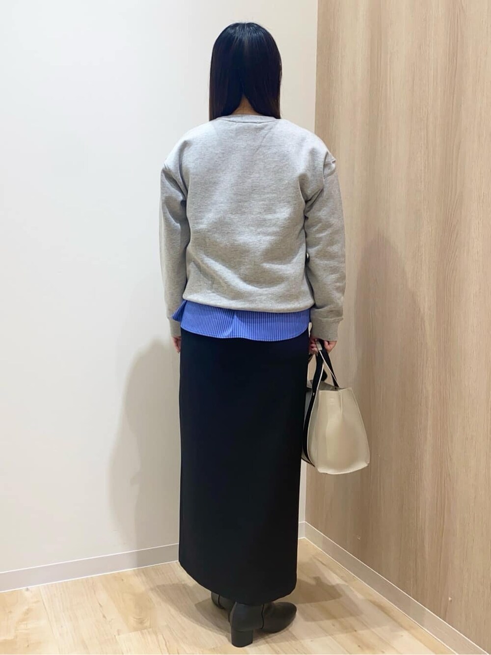 グレー系のスウェット、ブルー系のタンクトップ、ブラック系のスカートを着用したレディースの冬コーディネートの3枚目の写真