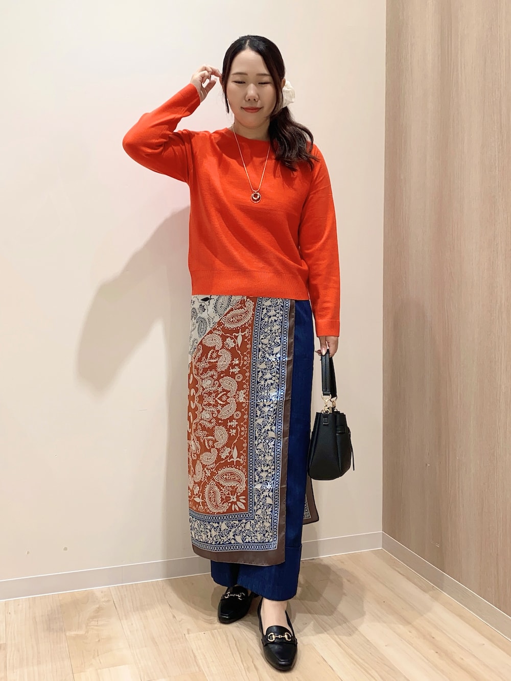 レッド系のニット/セーター、ブルー系のデニムパンツ、ブラック系のショルダーバッグを着用したレディースの秋コーディネートの2枚目の写真
