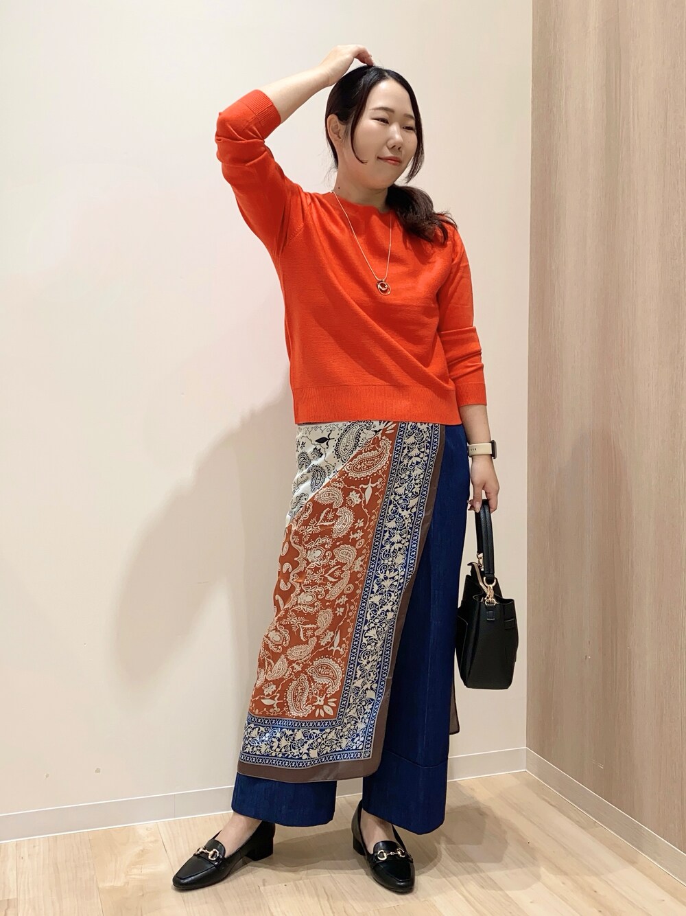 レッド系のニット/セーター、ブルー系のデニムパンツ、ブラック系のショルダーバッグを着用したレディースの秋コーディネートの3枚目の写真