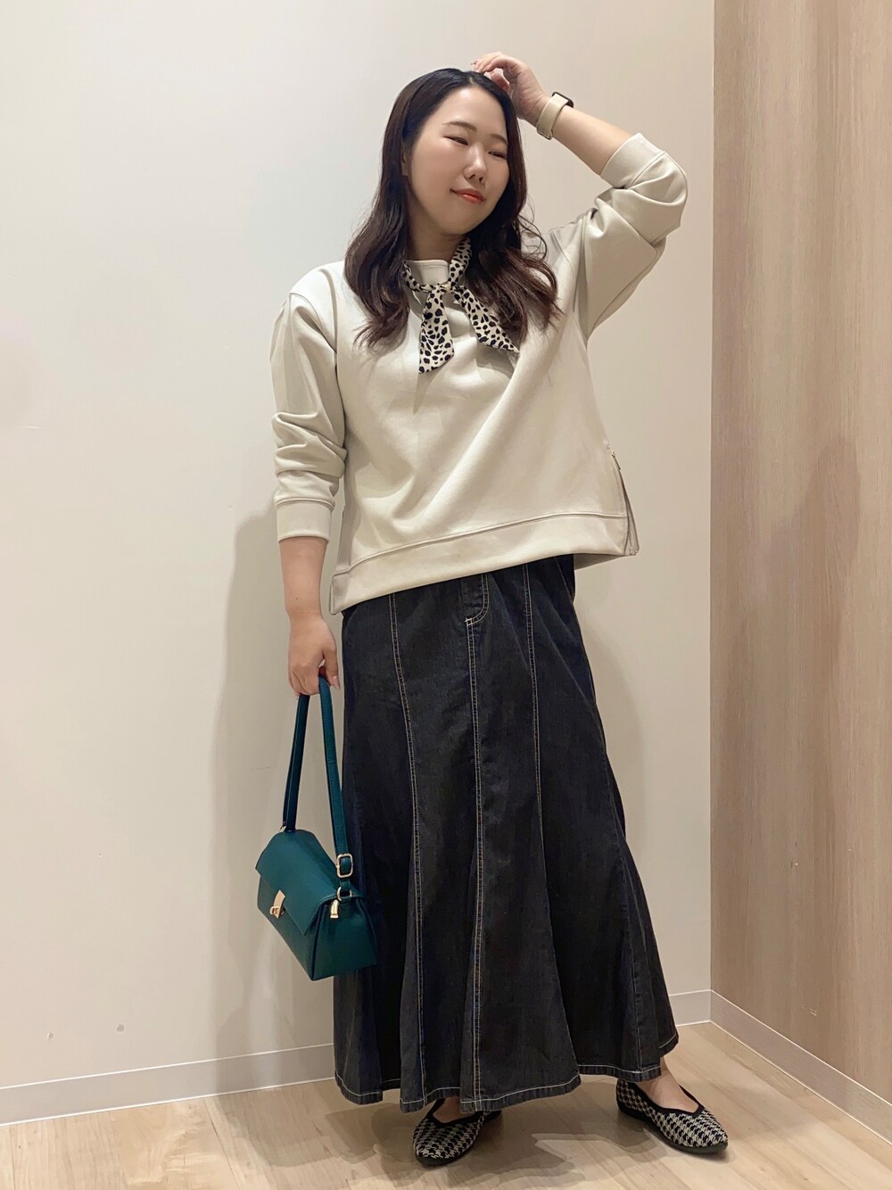 ベージュ系のTシャツ/カットソー、ブラック系のデニムスカート、グリーン系のショルダーバッグを着用したレディースの秋コーディネートの2枚目の写真