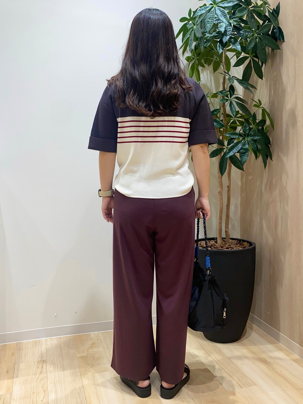 グレー系のニット/セーター、ブラウン系のその他パンツ、ブラック系のショルダーバッグを着用したレディースの夏コーディネートの4枚目の写真