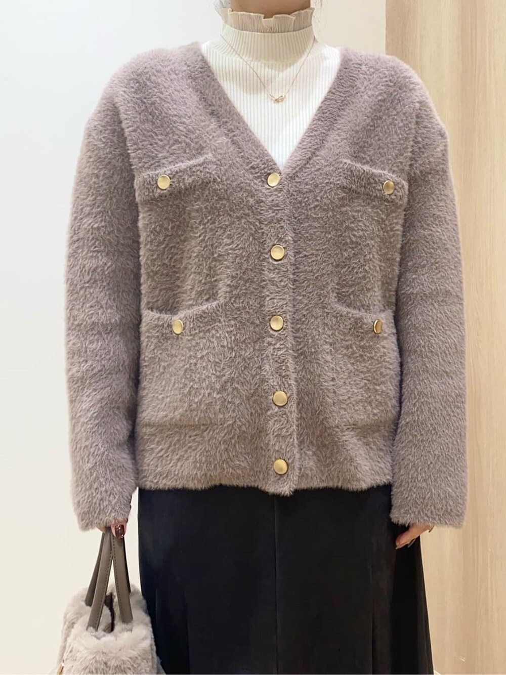 ベージュ系のカーディガン/ボレロ、ホワイト系のニット/セーター、グレー系のスカートを着用したレディースの秋コーディネートの4枚目の写真