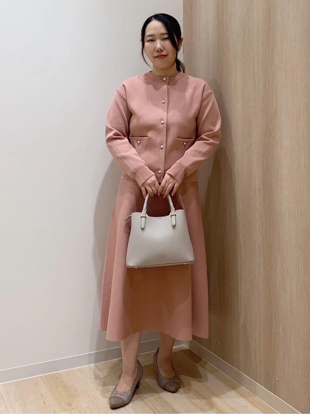 ピンク系のカーディガン/ボレロ、ピンク系のスカート、グレー系のトートバッグを着用したレディースの春コーディネートの2枚目の写真