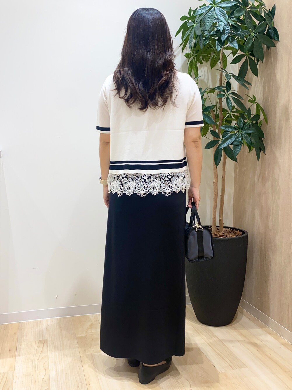 ホワイト系のニット/セーター、ブラック系のスカート、グレー系のボストンバッグを着用したレディースの夏コーディネートの4枚目の写真