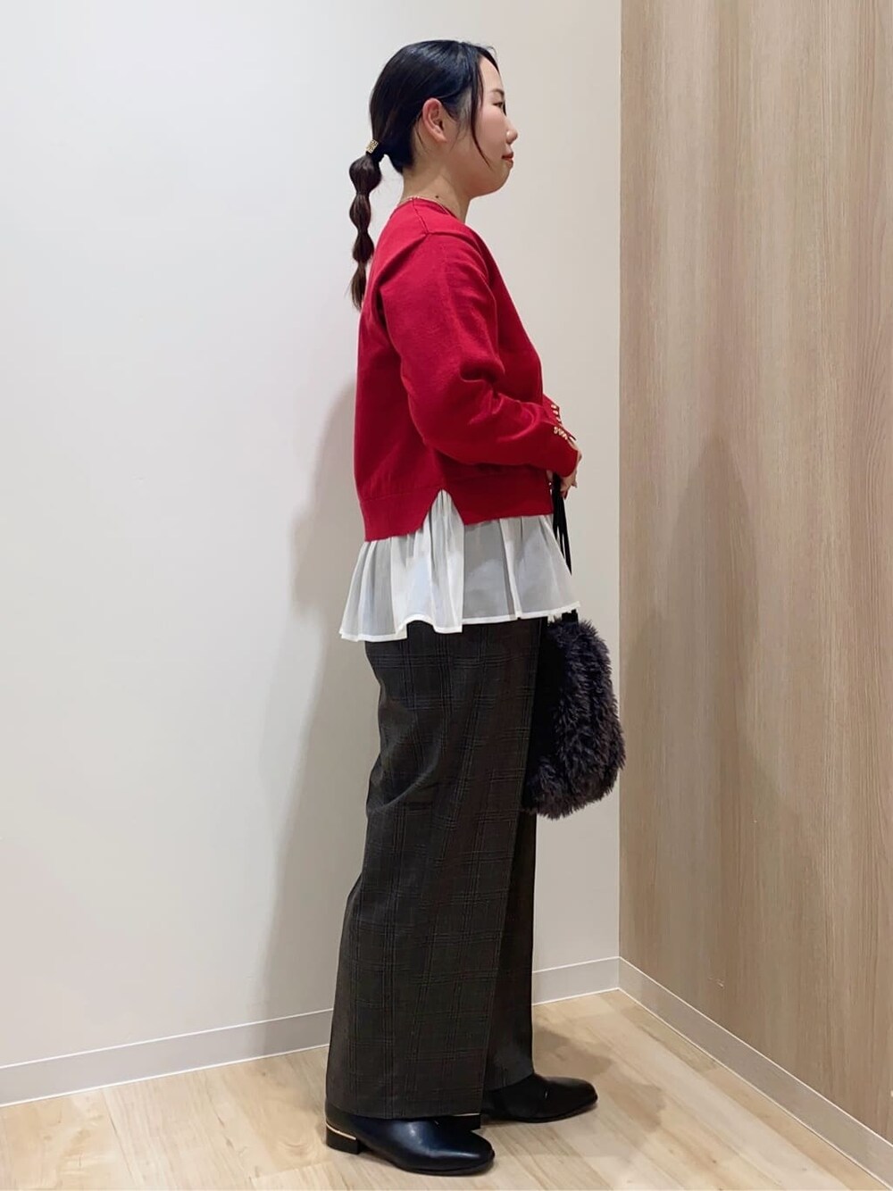 レッド系のニット/セーター、ブラック系のその他パンツ、グレー系のショルダーバッグを着用したレディースの冬コーディネートの2枚目の写真