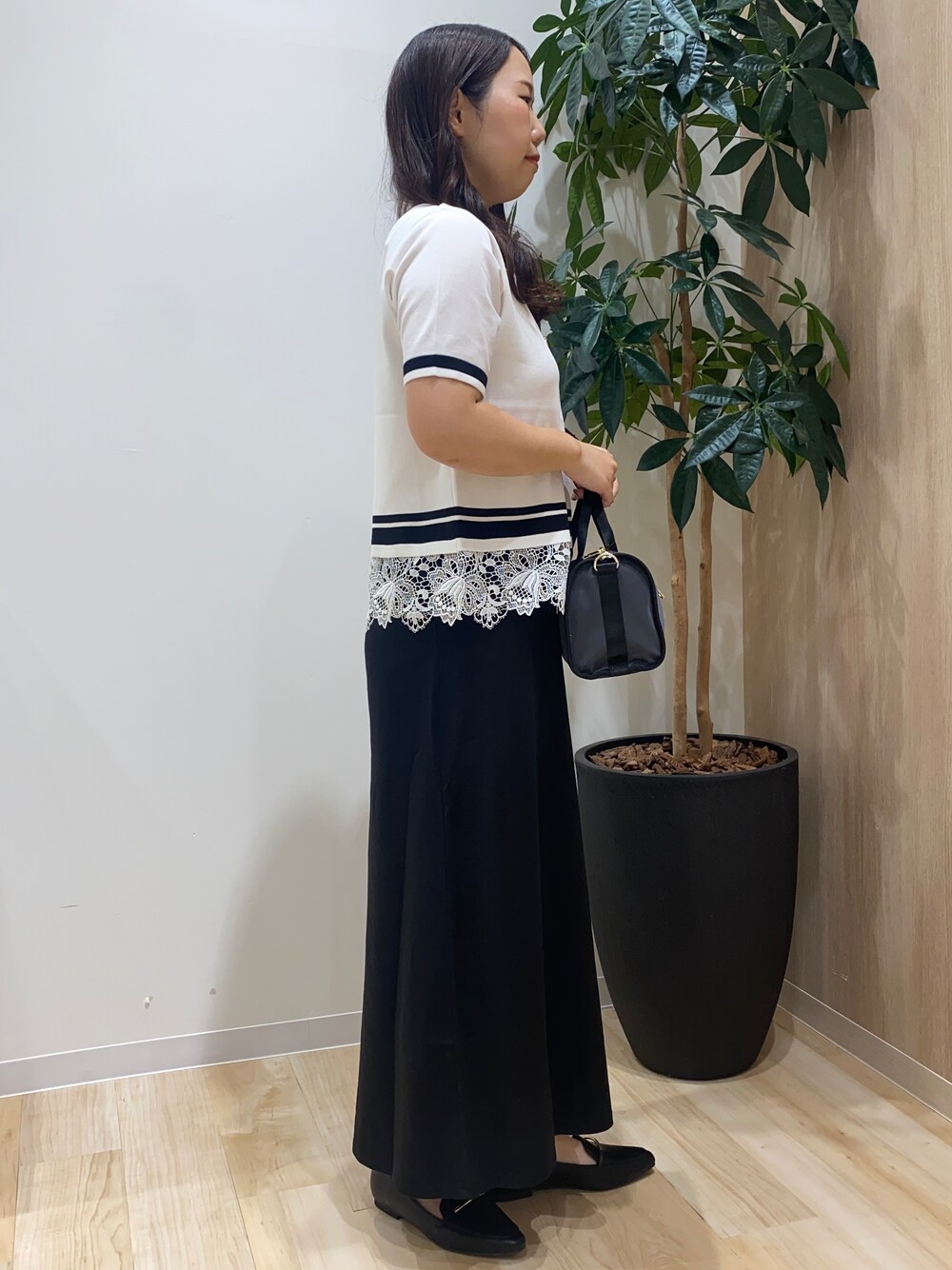 ホワイト系のニット/セーター、ブラック系のスカート、グレー系のボストンバッグを着用したレディースの夏コーディネートの3枚目の写真