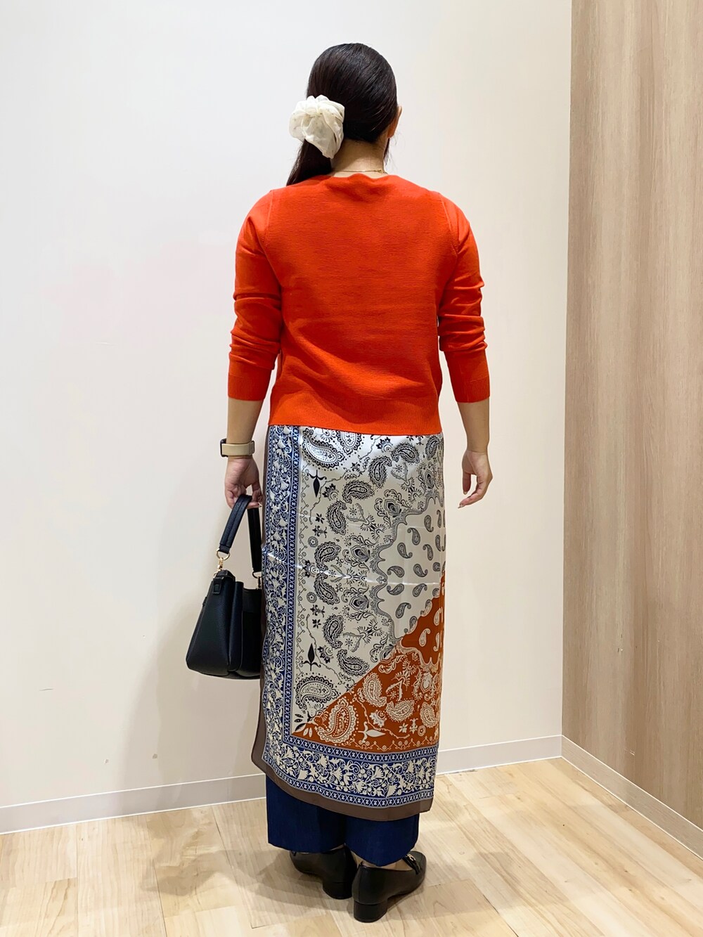 レッド系のニット/セーター、ブルー系のデニムパンツ、ブラック系のショルダーバッグを着用したレディースの秋コーディネートの5枚目の写真