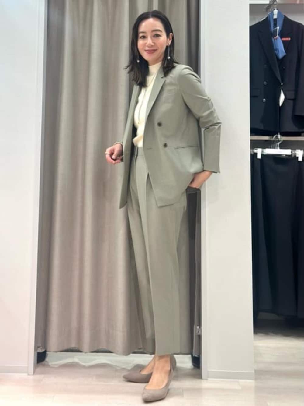 ベージュ系のニット/セーター、グリーン系のテーラードジャケット、グリーン系のスラックスを着用したレディースの冬コーディネートの2枚目の写真