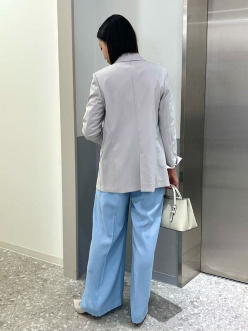 ブルー系のスラックス、グレー系のテーラードジャケットを着用したレディースの春コーディネートの3枚目の写真