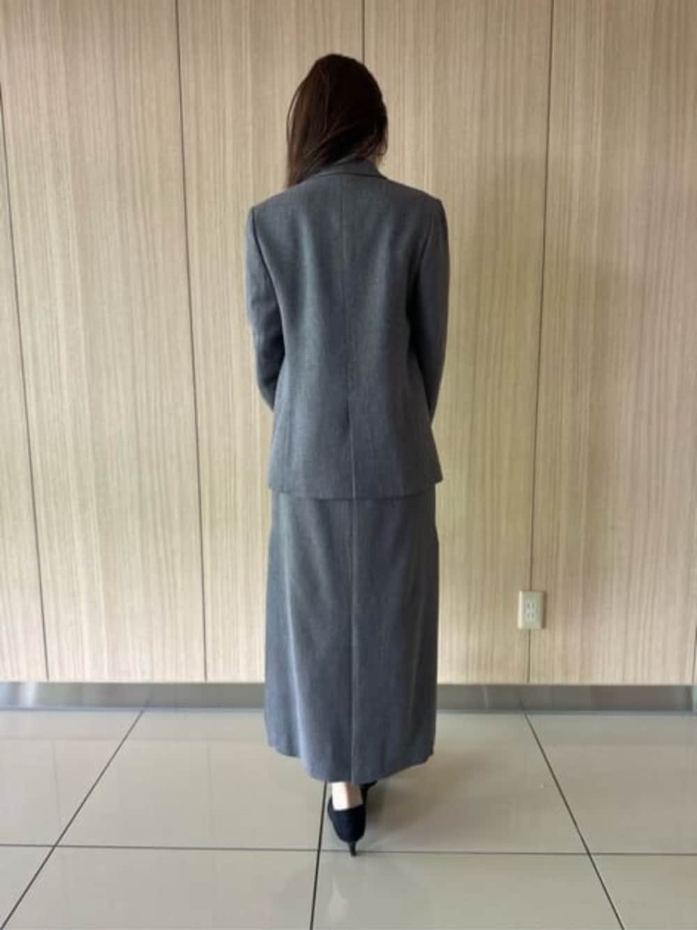 グレー系のスカート、グレー系のテーラードジャケット、ブラック系のショルダーバッグを着用したレディースの冬コーディネートの3枚目の写真