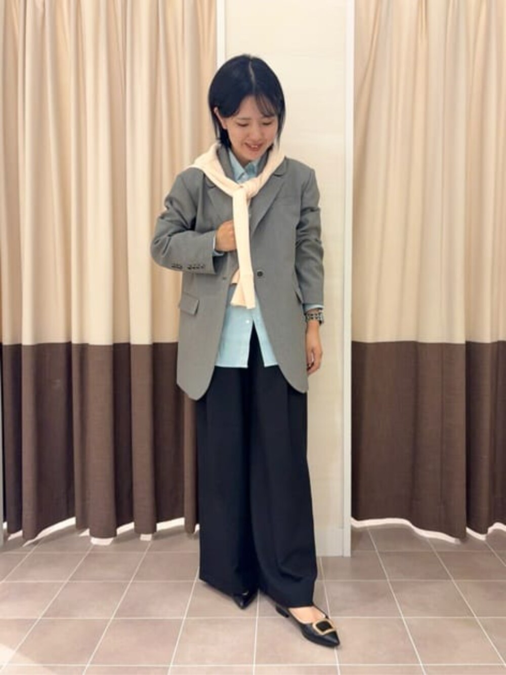 グレー系のテーラードジャケット、ブラック系のスラックス、グリーン系のシャツ/ブラウスを着用したレディースの冬コーディネートの3枚目の写真