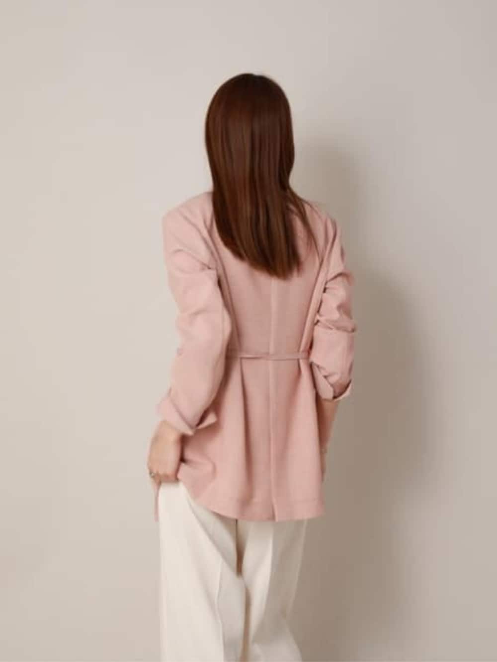 オレンジ系のテーラードジャケット、ホワイト系のスラックスを着用したレディースの冬コーディネートの2枚目の写真