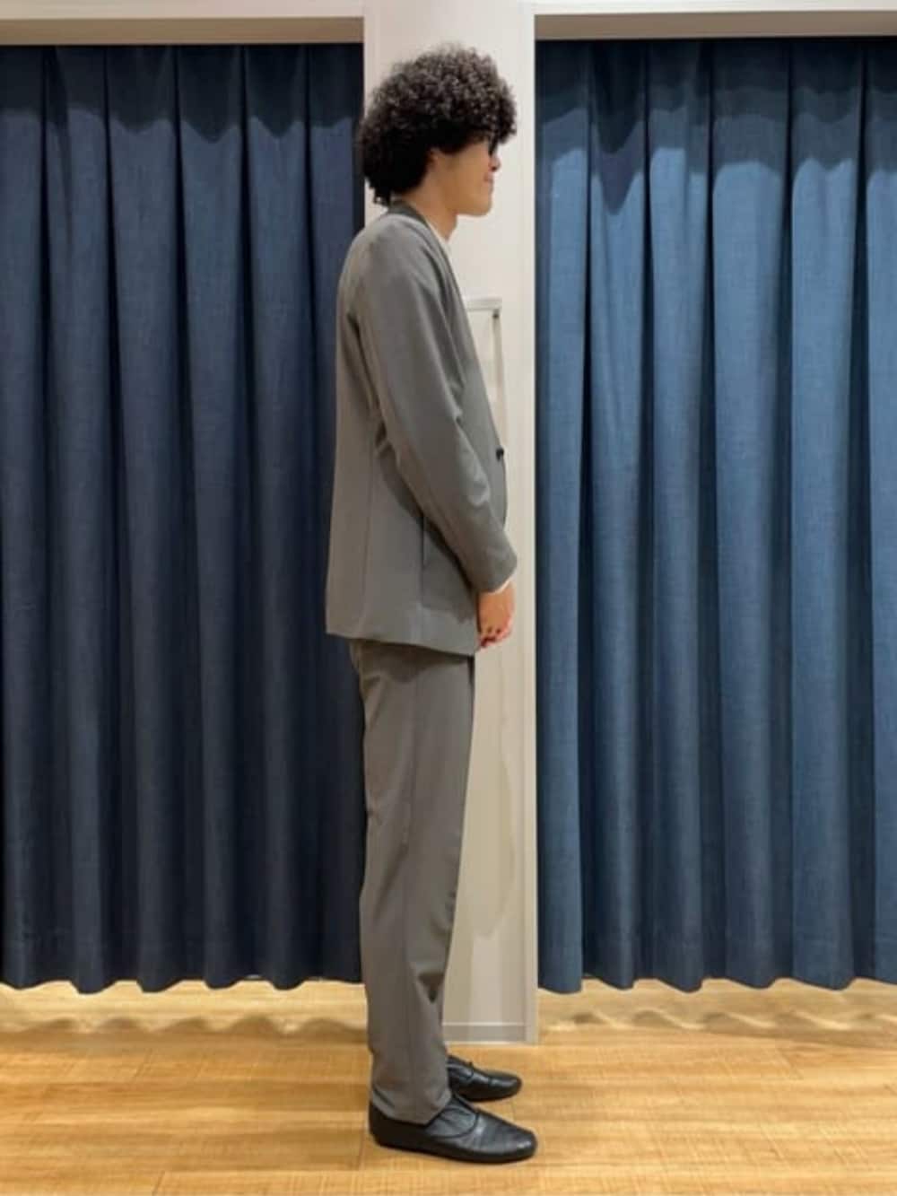 グレー系のスラックス、グレー系のテーラードジャケット、ホワイト系のTシャツ/カットソーを着用したメンズの冬コーディネートの3枚目の写真