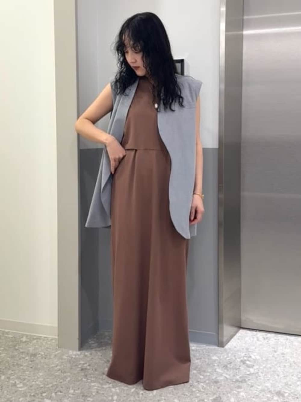 グレー系のベスト、ブラウン系のワンピースを着用したレディースの冬コーディネートの2枚目の写真