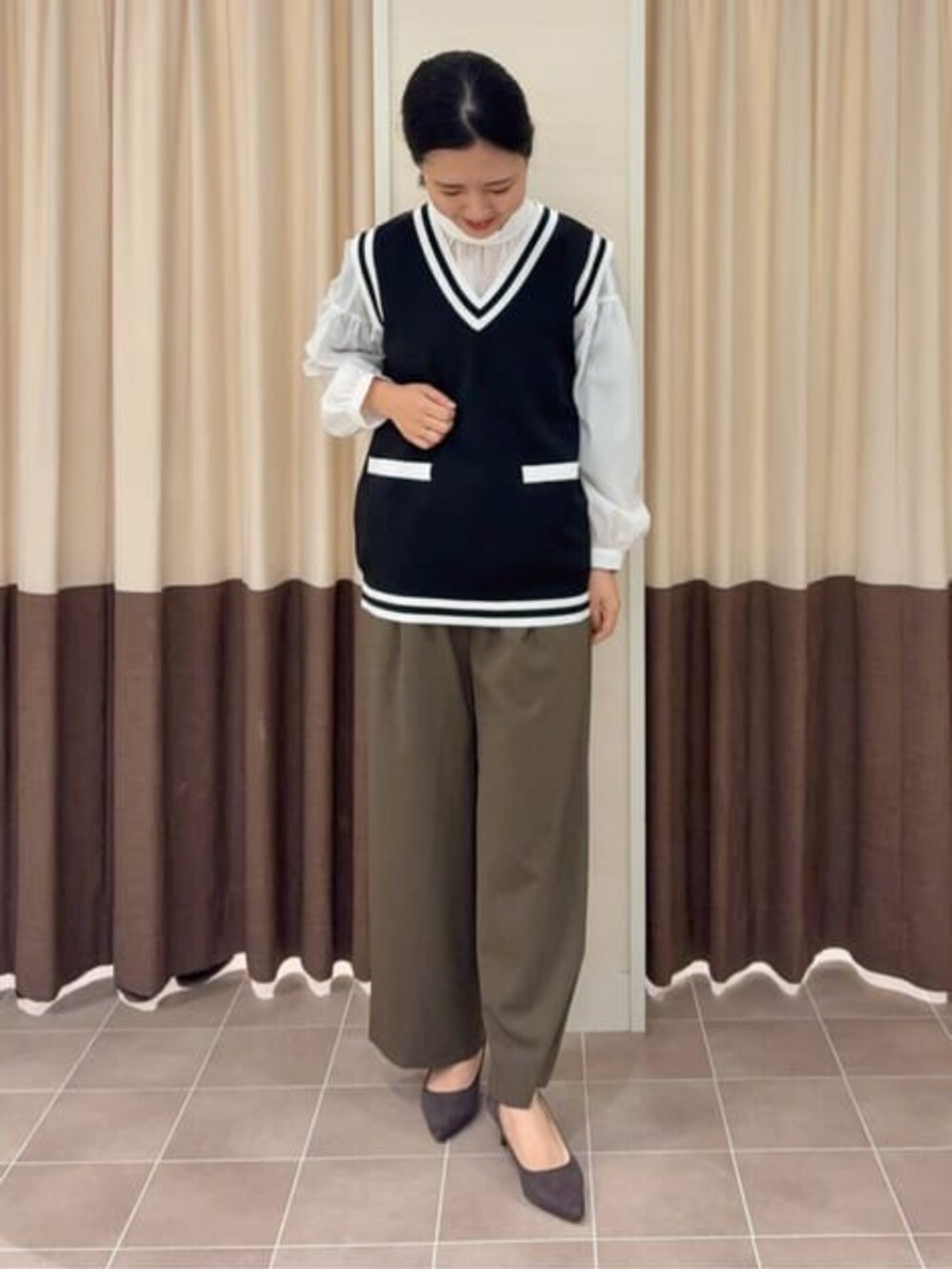 ブラック系のベスト、グリーン系のその他パンツ、ブルー系のテーラードジャケットを着用したレディースの春コーディネートの2枚目の写真