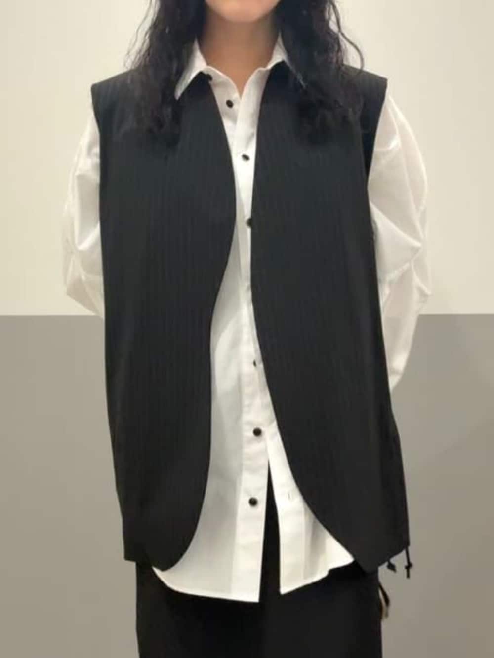 ホワイト系のシャツ/ブラウス、ブラック系のスカート、ブラック系のベストを着用したレディースの冬コーディネートの4枚目の写真