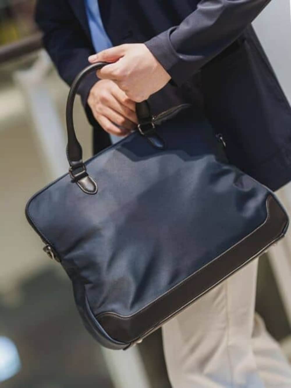 ブルー系のビジネスバッグ、ホワイト系のスラックスを着用したメンズの春コーディネートの7枚目の写真