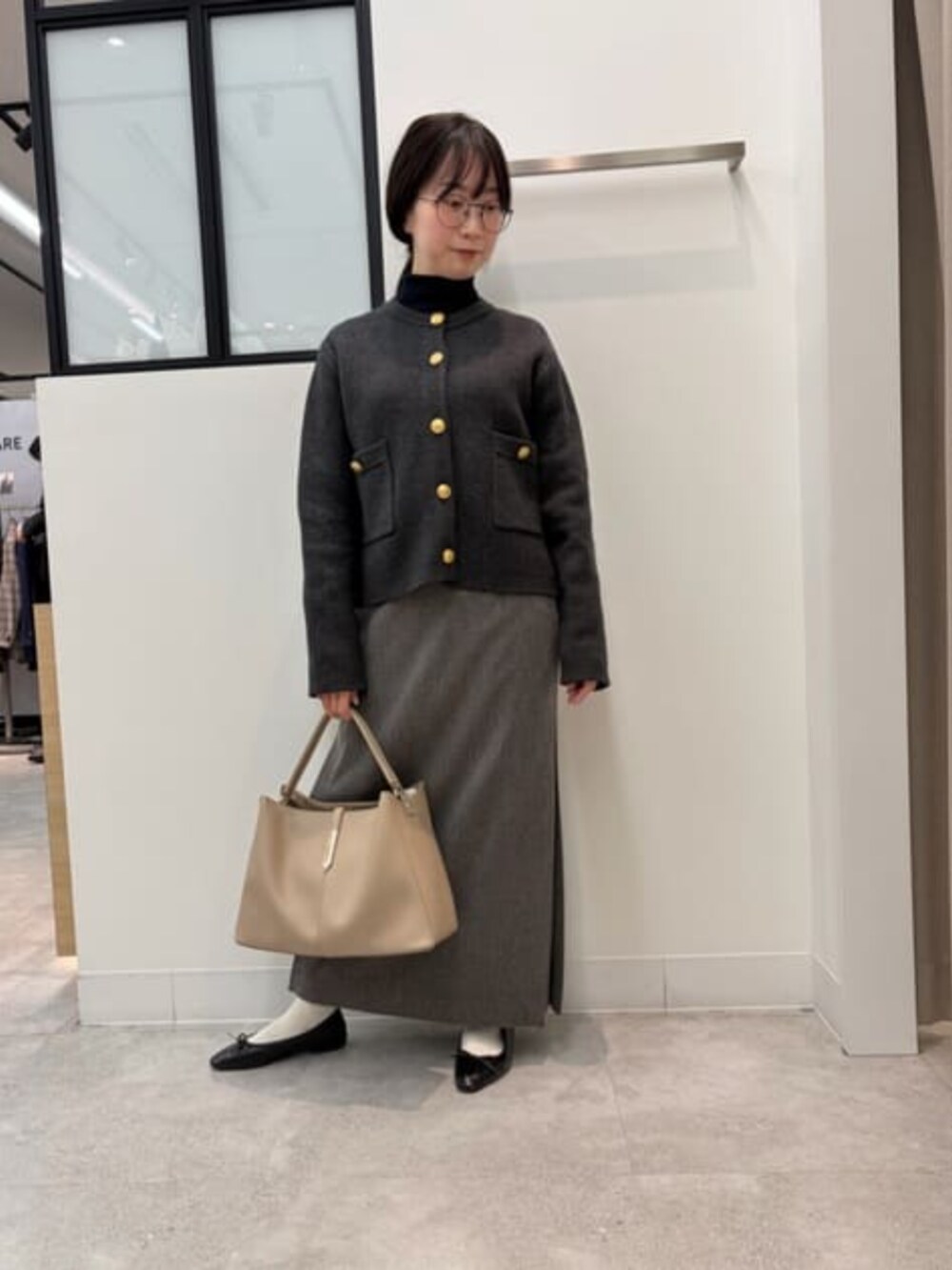 グレー系のノーカラージャケット、ベージュ系のショルダーバッグ、グレー系のスカートを着用したレディースの冬コーディネートの2枚目の写真