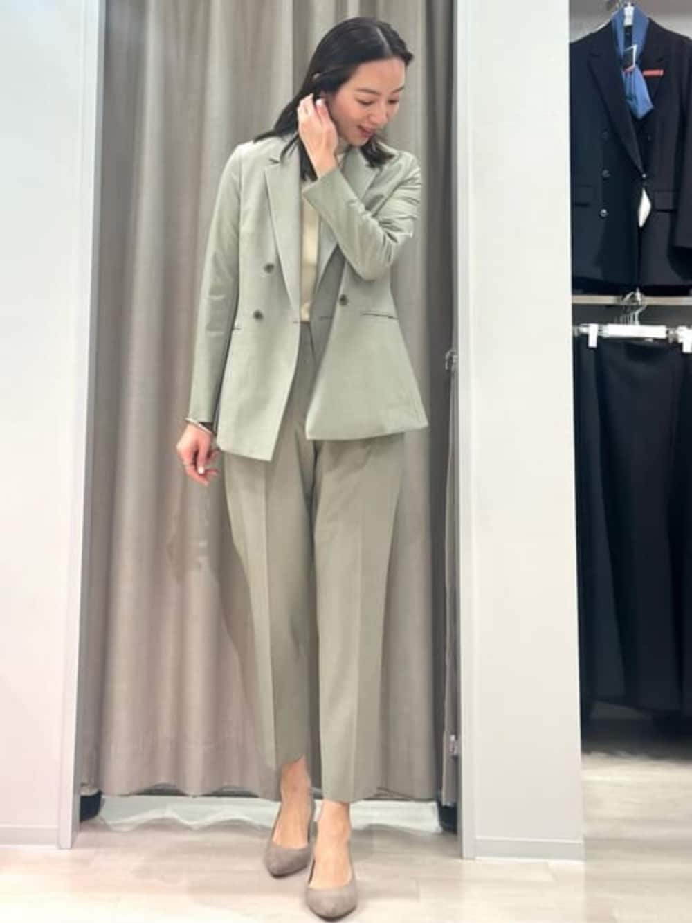 ベージュ系のニット/セーター、グリーン系のテーラードジャケット、グリーン系のスラックスを着用したレディースの冬コーディネートの3枚目の写真