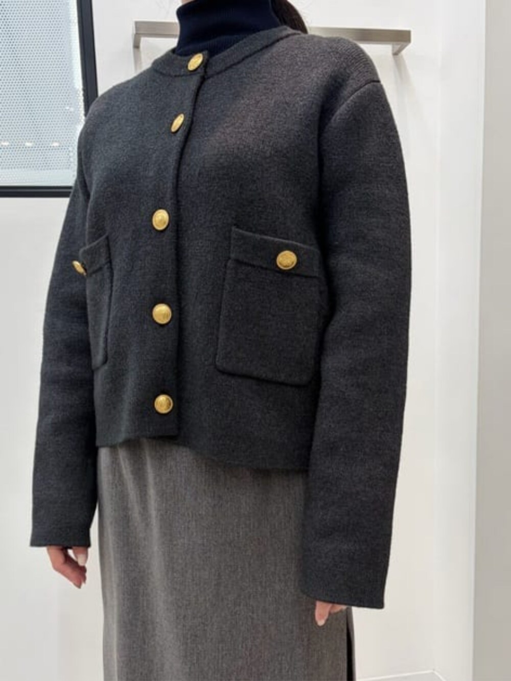 グレー系のノーカラージャケット、ベージュ系のショルダーバッグ、グレー系のスカートを着用したレディースの冬コーディネートの3枚目の写真