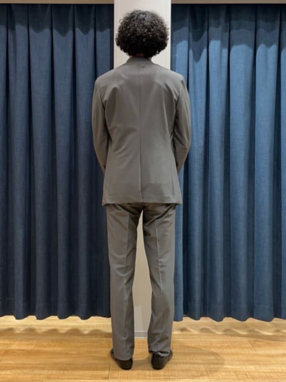 グレー系のスラックス、グレー系のテーラードジャケット、ホワイト系のTシャツ/カットソーを着用したメンズの冬コーディネートの2枚目の写真