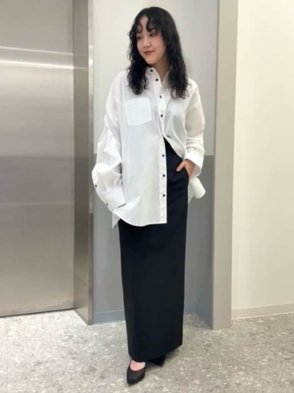 ホワイト系のシャツ/ブラウス、ブラック系のスカート、ブラック系のベストを着用したレディースの冬コーディネートの5枚目の写真