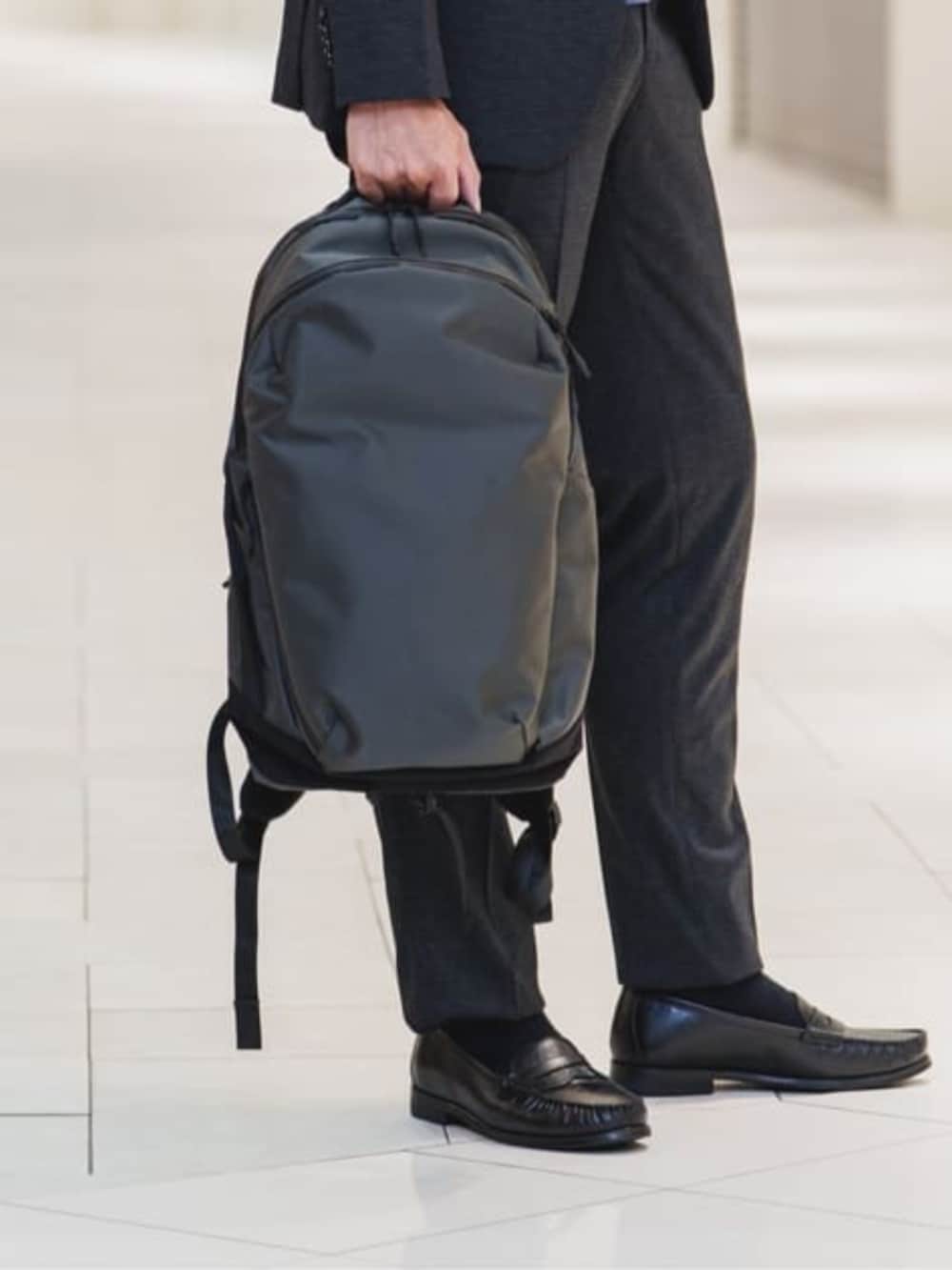 グレー系のバックパック/リュック、グレー系のテーラードジャケット、グレー系のスラックスを着用したメンズの冬コーディネートの9枚目の写真