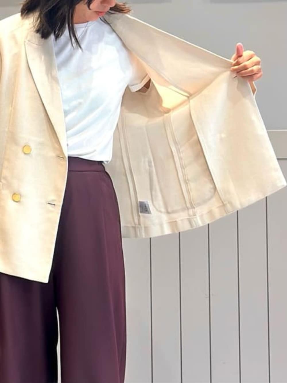 パープル系のスラックス、ホワイト系のテーラードジャケットを着用したレディースの冬コーディネートの6枚目の写真