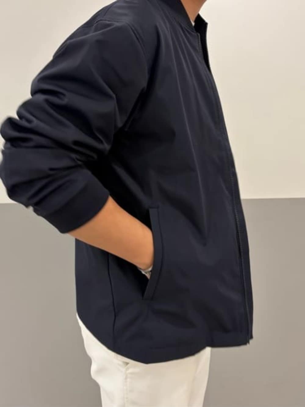 ホワイト系のテーラードジャケット、ブルー系のMA-1、ホワイト系のスラックスを着用したメンズの春コーディネートの2枚目の写真