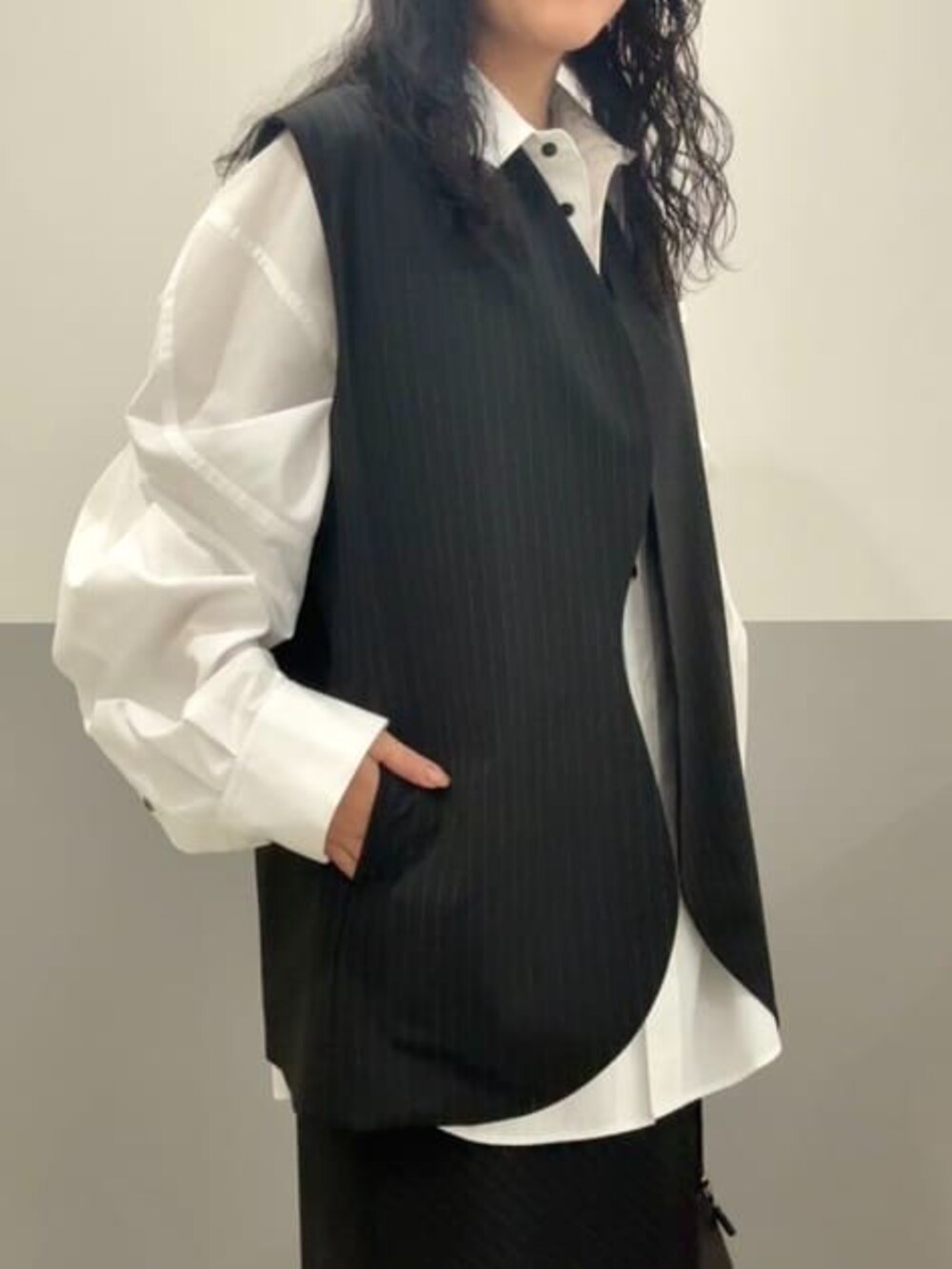 ホワイト系のシャツ/ブラウス、ブラック系のスカート、ブラック系のベストを着用したレディースの冬コーディネートの3枚目の写真