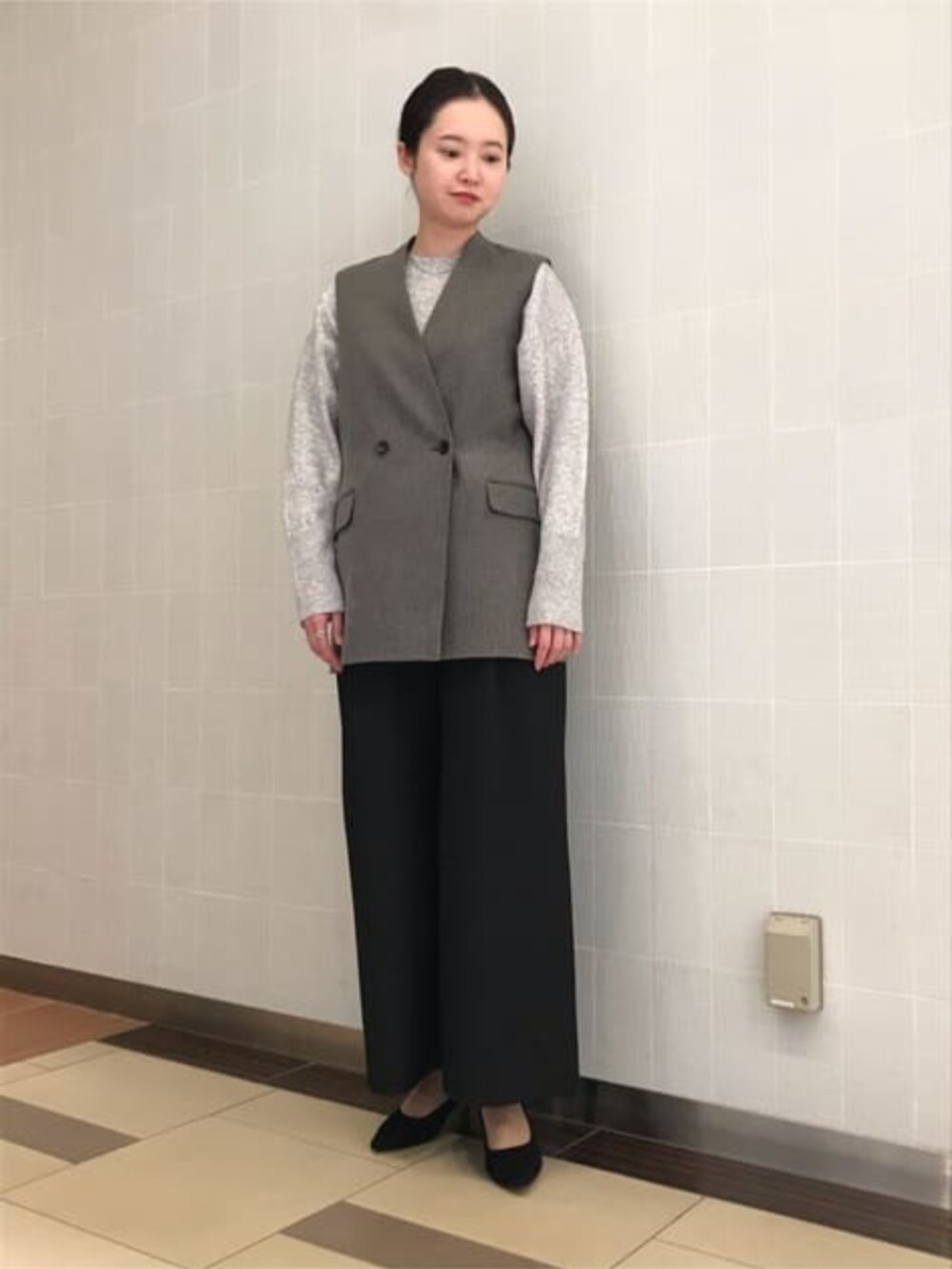 グレー系のニット/セーター、グレー系のベスト、ブラック系のスラックスを着用したレディースの冬コーディネートの2枚目の写真