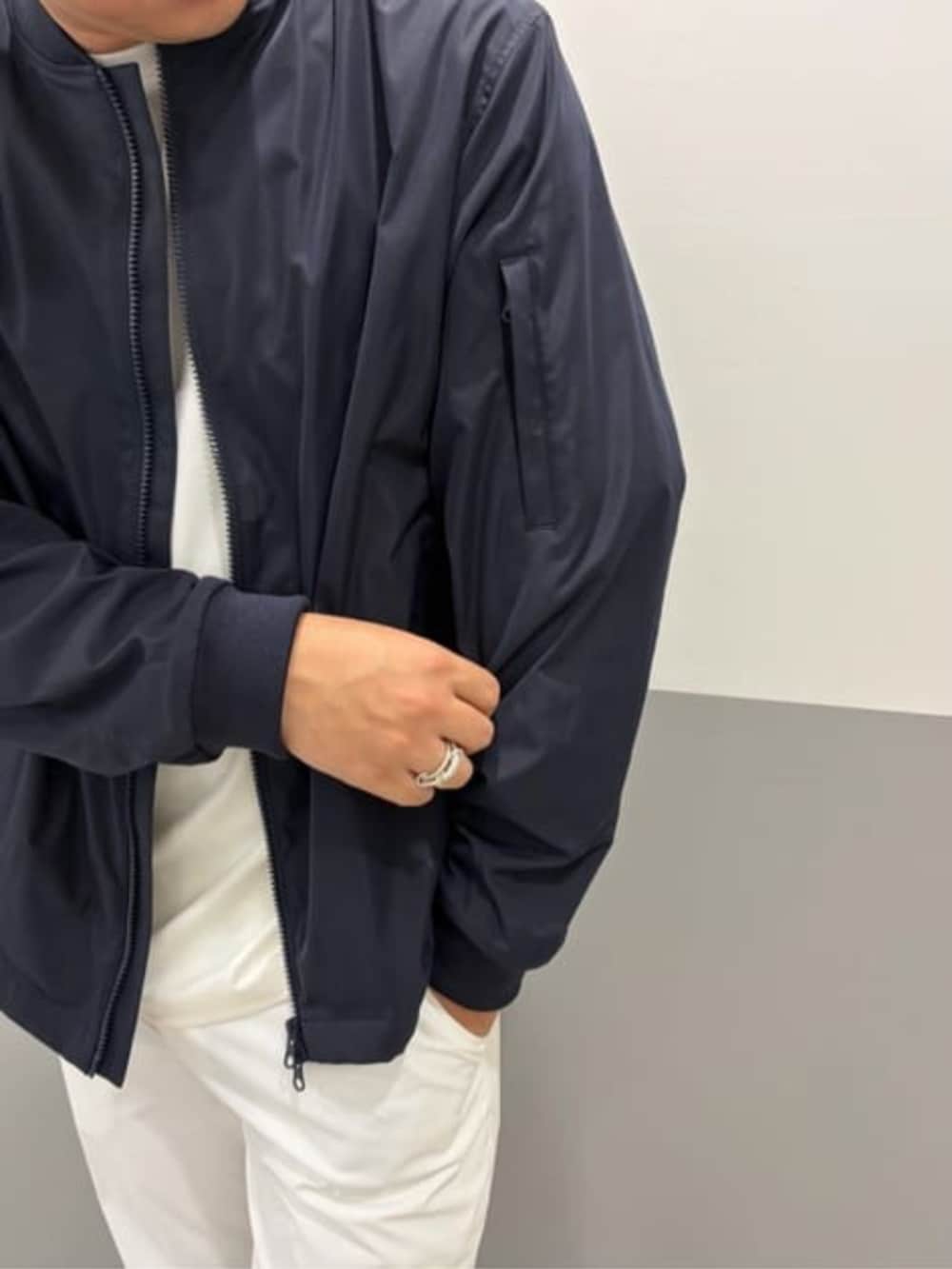 ホワイト系のテーラードジャケット、ブルー系のMA-1、ホワイト系のスラックスを着用したメンズの春コーディネートの3枚目の写真