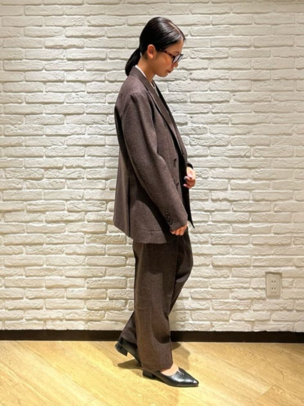 ブラウン系のスラックス、パープル系のテーラードジャケット、グレー系のニット/セーターを着用したレディースの冬コーディネートの3枚目の写真