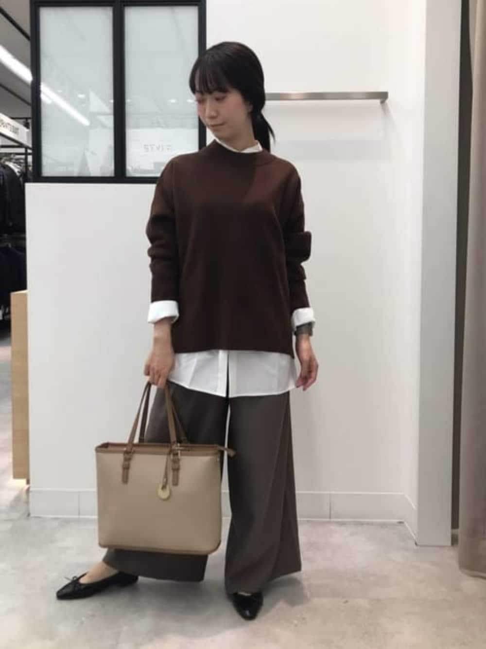 ブラウン系のニット/セーター、グリーン系のスラックス、ホワイト系のシャツ/ブラウスを着用したレディースの冬コーディネートの2枚目の写真