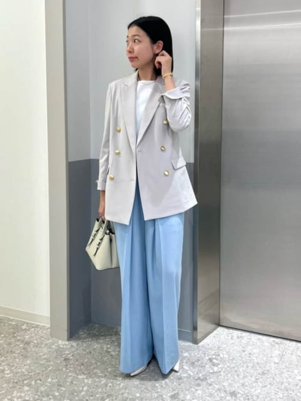 ブルー系のスラックス、グレー系のテーラードジャケットを着用したレディースの春コーディネートの2枚目の写真