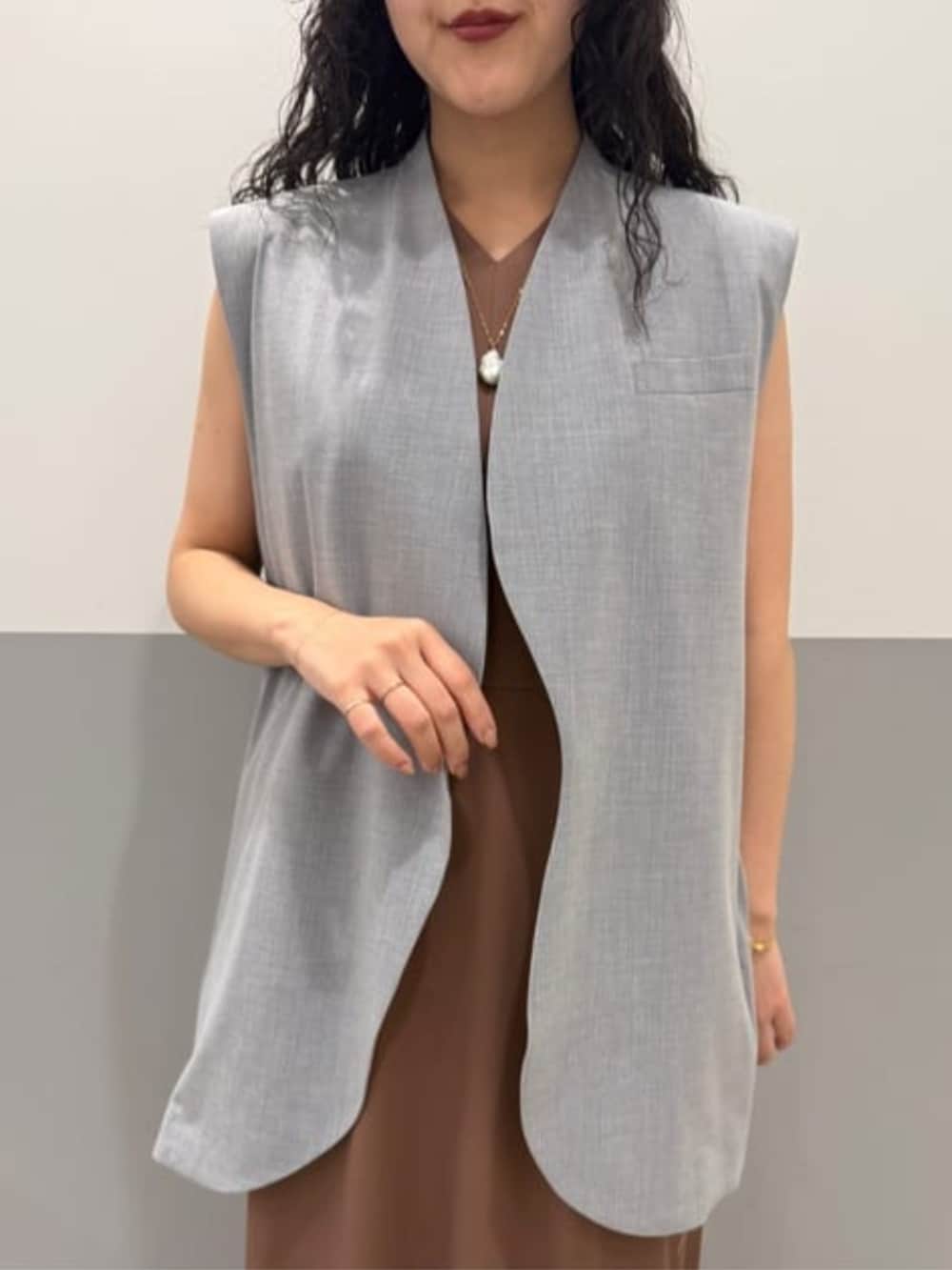 グレー系のベスト、ブラウン系のワンピースを着用したレディースの冬コーディネートの3枚目の写真