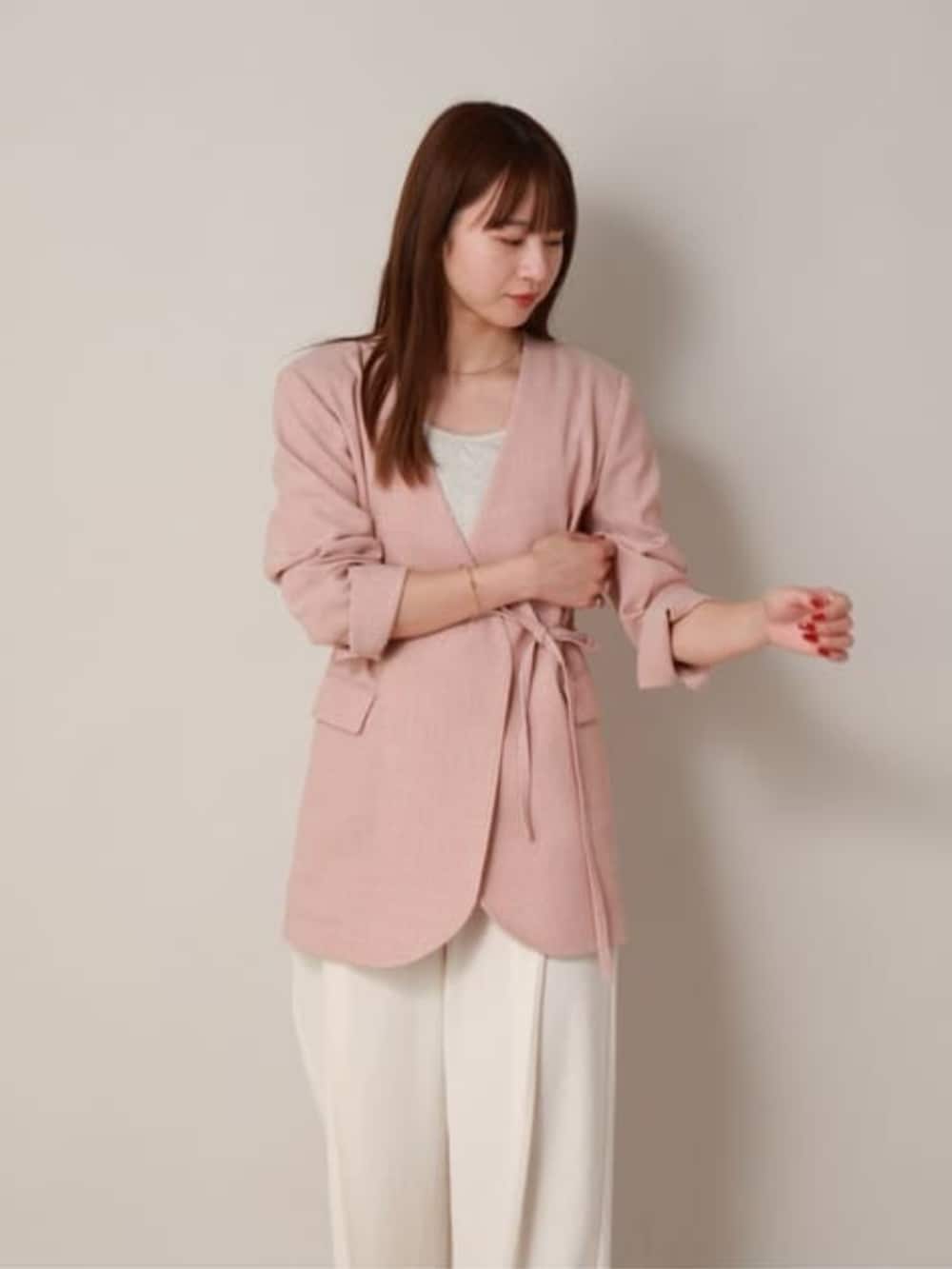 オレンジ系のテーラードジャケット、ホワイト系のスラックスを着用したレディースの冬コーディネートの3枚目の写真